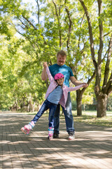 dad teaches daughter to roller skate.