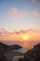 Obraz premium Sunset view of a stunning paradise cove embedded by peculiar rock formations at Nas beach on the raw island of Ikaria.