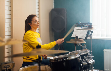 A girl learns how to play the drums from the notes.