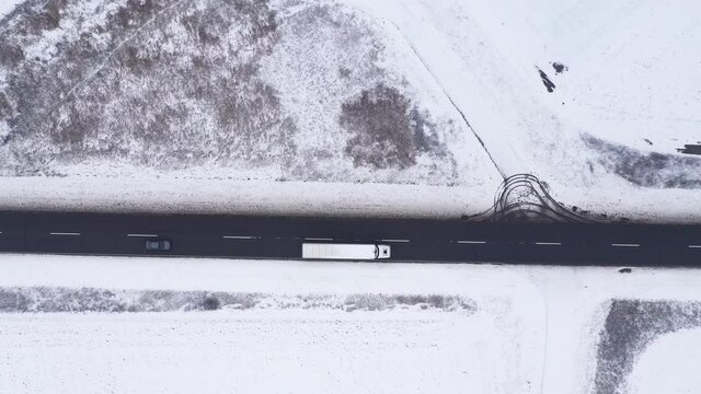 Aerial shot of semitrailer truck and many cars on the road in winter, top down drone footage of traffic on wintry roadway