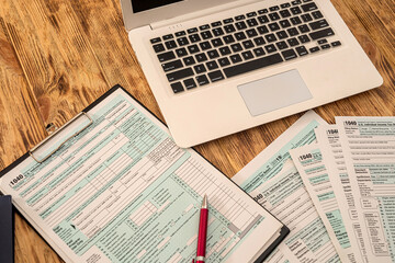 Obraz premium on a wooden table are a laptop, calculator, dollar bills, pen and tax forms