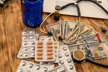 on a wooden table are American dollar bills on which are poured white pills from a bottle
