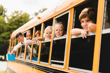 Schoolchildren classmates pupils looking out of the school bus waiting for new educational year...