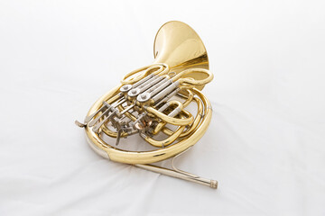 A shiny lacquered French horn in a white box