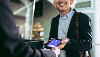 Man showing flight ticket to staff on phone - obrazy, fototapety, plakaty