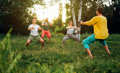 Trainer shows how to do manu stance exercise. Group learning qigong in nature. - obrazy, fototapety, plakaty