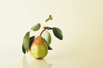 Ripe pear with leaves on a yellow background.