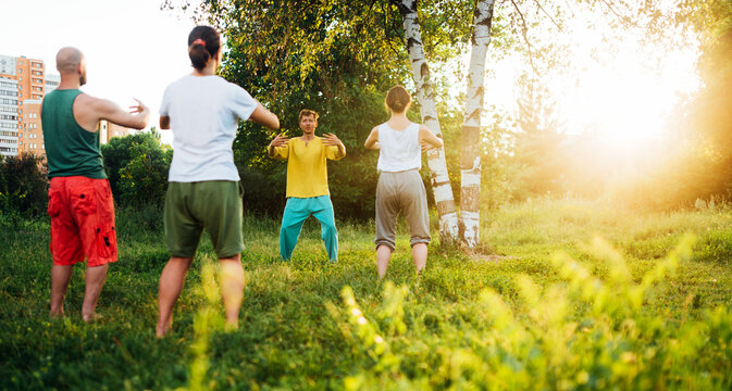 Trainer shows how to do mabu pose. Group wushu classes in nature.