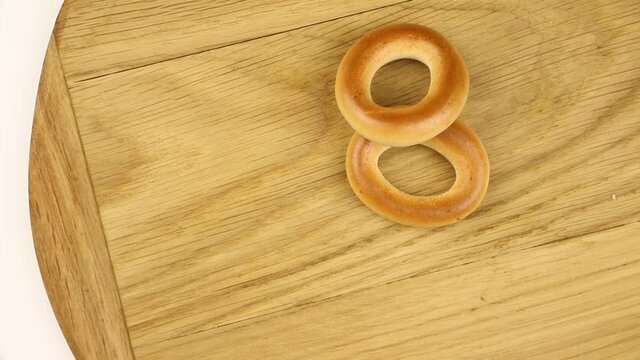 Small dry bages on a wooden board on a kitchen, wheat food concept video, rotating composition