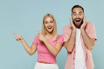 Young surprised couple two friends family man woman in casual clothes point index finger aside...