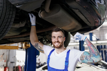 Strong young male professional technician mechanic man wears denim blue overalls t-shirt show...