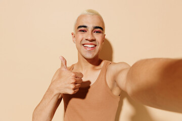 Close up young blond latin gay man with make up in beige tank shirt doing selfie shot pov on mobile...