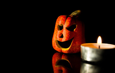 Small ceramic Halloween pumpkin with a candle. Jack-o'-lantern composition on black background with...