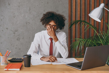 Young tired exhausted sad sick african american employee business man in classic shirt tie close...