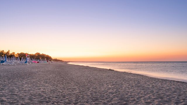 Panorama of adriatic sea and beach with umbrella at sunrise