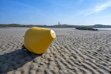 Gelbe Boje am Strand von Berck sur mer / Pas de Calais / Nordfrankreich. Im Hintergrund erkennt man den Leuchtturm auf der Landzunge. - obrazy, fototapety, plakaty
