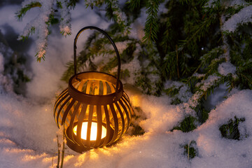 A candle in a round candlestick under a snow-covered Christmas tree. Christmas mood of a festive evening
