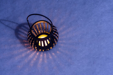 A candle in a round candlestick in the snow at night. Christmas mood of a festive evening