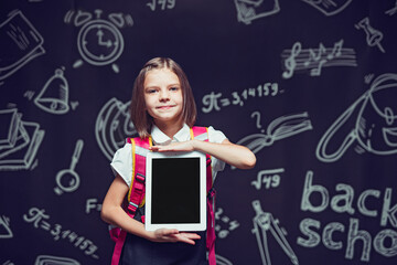 Little pupil preparing to go to school with backpack showing the tablet. Back to school concept 