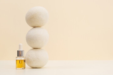 Balancing Wool Dryer Balls And Oil Aroma Bottle On Beige Background. Eco Friendly Laundry Supplies....