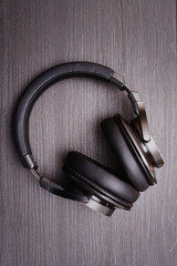 Wireless full-size, professional music headphones on a dark background with a wood texture.