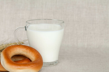 bagels, wheat ears and a glass of milk on a linen background, space for text