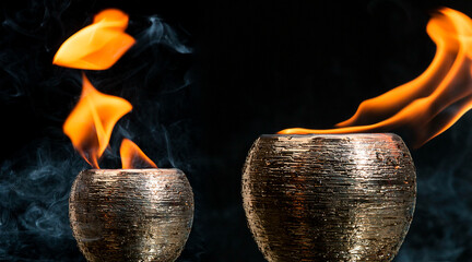Potes dourados de cerâmica saindo fogo de dentro envolvido por fumaça em um fundo preto. 