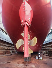 Dry-cargo ship in dry dock for repairs and maintenance at a shipyard. The stern of a large ship...
