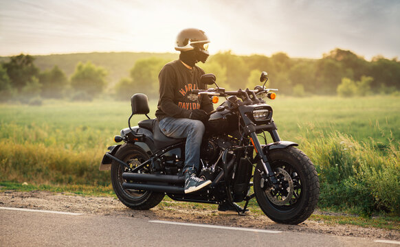 Biker sits on a Harley Davidson Fat Bob 114 2020 motorcycle in the field near the track. Kharkiv, Ukraine-15 July 2021.