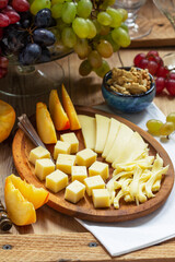 An appetizer of various types of cheese, grapes and walnuts, served with wine. Rustic style.