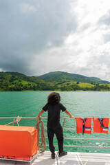 Vertical de un hombre con cabello rizado de espalda en una embarcación en el lago Arenal en Costa Rica - obrazy, fototapety, plakaty