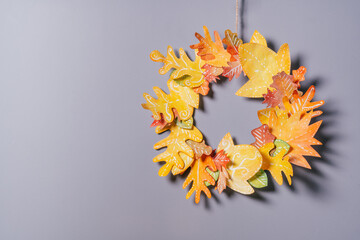 Homemade autumn yellow-red paper wreath on a gray wall background, seasonal DIY