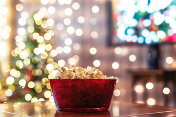 Christmas eve. Red bowl with popcorn on the table. Home cinema. Tv. Cropped, close up