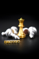 A chess board game. The winning business concept: competition and management. A golden chess piece on a dark background. Word winner. Copy space for text.