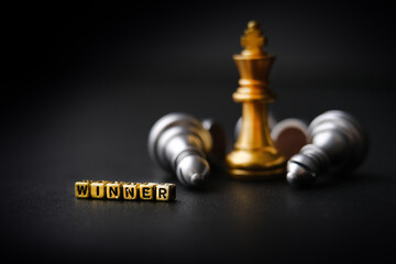 The winning business concept: competition and management. A golden chess piece on a dark background. Word winner. Copy space for text. Horizontal format