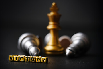 The golden queen of chess is surrounded by a number of fallen silver chess pieces, a business strategy concept. The concept of the winner. The word - victory. Copy space for your text.
