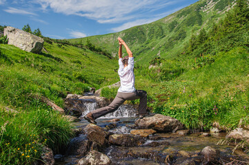 Sports girl doing yoga on the rocks above the river in the Ukrainian Carpathians