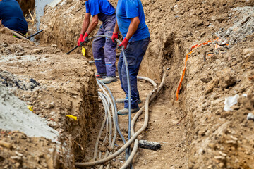 Workers lay underground cable - obrazy, fototapety, plakaty