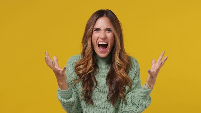 Displeased irritated dissatisfied disconcerted angry young brunette woman 30s years old wears mint sweater closed eyes put hand on head scream yell isolated on plain yellow background studio portrait