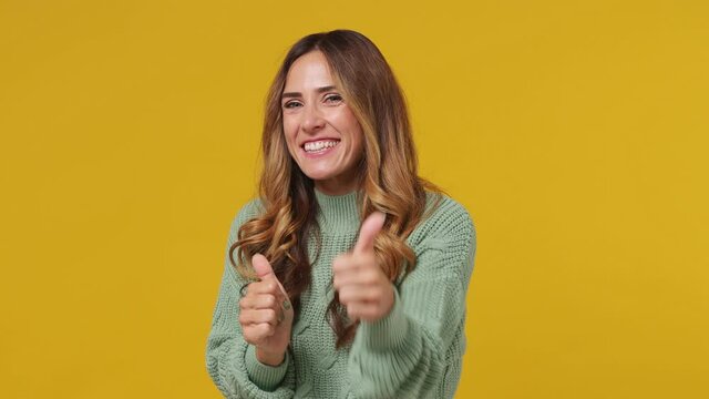 Excited young brunette woman 30s years old wears mint sweater point index finger camera on you motivating encourage showing thumb up like gesture isolated on plain yellow background studio portrait