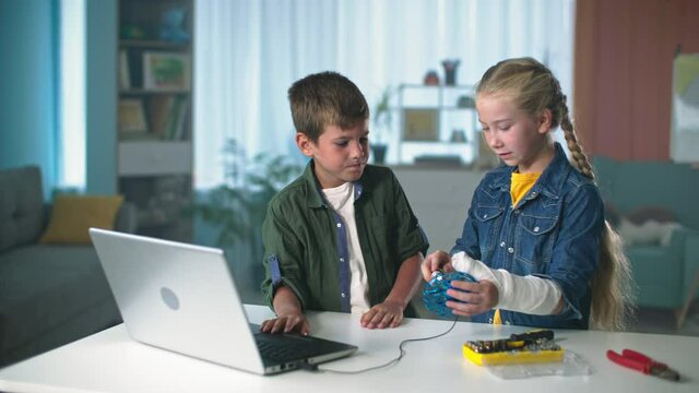 computer programming of technology by children, little boy and girl with plaster on arm connected the drone via USB cable to the laptop at home
