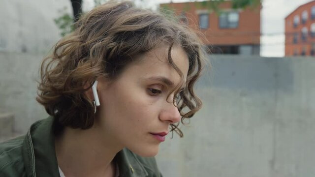 Young beautiful candid woman put wireless earphones in to enjoy soft rhythmical beats