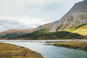Scenic landscape with mountain creek and motley mountains in autumn colors. Colorful autumn view to...