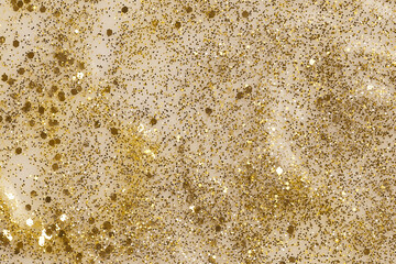 Shiny gold glittering background with soft selective focus. Nail polish texture.