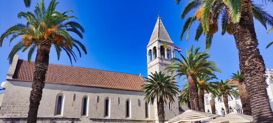 Fototapeta na wymiar Historic City of Trogir. Old stone church St. Lawrence Cathedral (Katedrala sv. Lovro). Palms and Croatian flag. Dalmatia. Croatia. Europe 