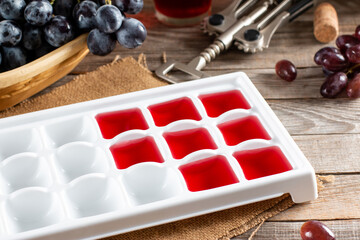 Wine in ice cube tray on a wooden table. Frozen wine