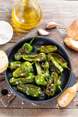 Grilled pepper Padron in a frying pan on a table. Spanish cuisine. Pimientos de Padron