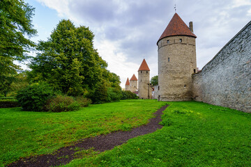 Fototapeta na wymiar Medieval wall with tall stone towers and red roofs in Tallinn Estonia.
