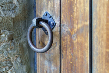 Detail of metal knocker on wooden door in medieval style.