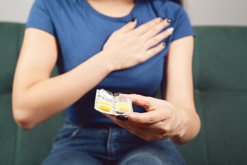 young woman holding pills and breasts